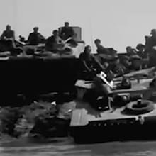 A black-and-white photo shows British soldiers in Tank at Lake Comacchio, Italy in April 1945.