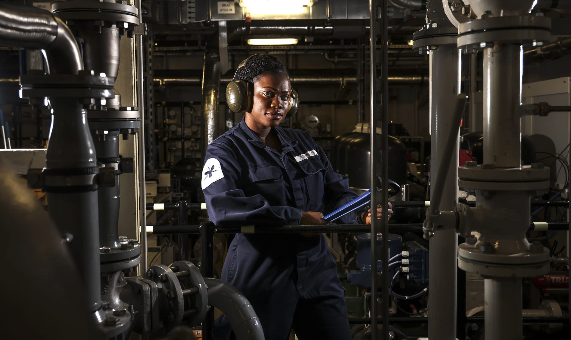 uniformed Royal Navy Mechanical Engineer checking key equipment on board aircraft carrier HMS Prince of Wales