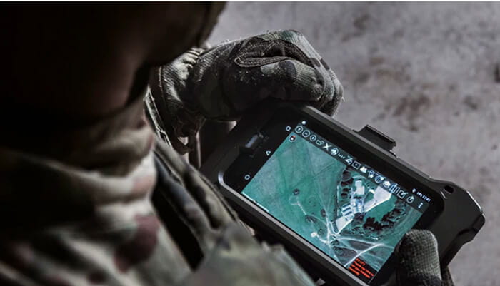 Over the shoulder image of a Royal Marine holding a computer screen, with a map showing on the screen.