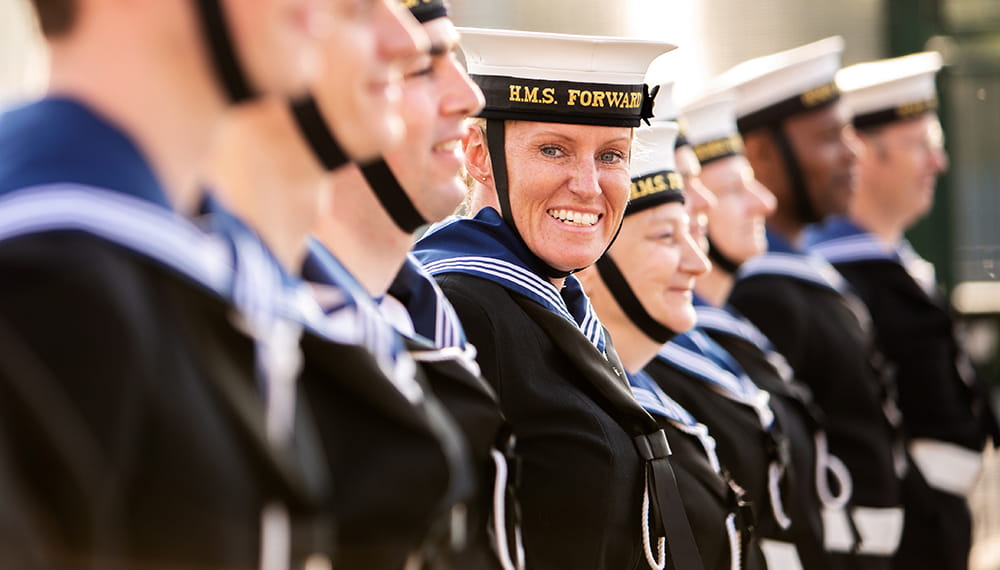 royal-navy-careers-services-07 HMS Forward personnel standing in a line at the Royal Navy Reserve unit in Birmingham. One sailor smiles at the camera.
