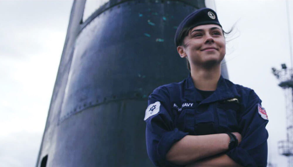 A submariner smiling in front of a submarine