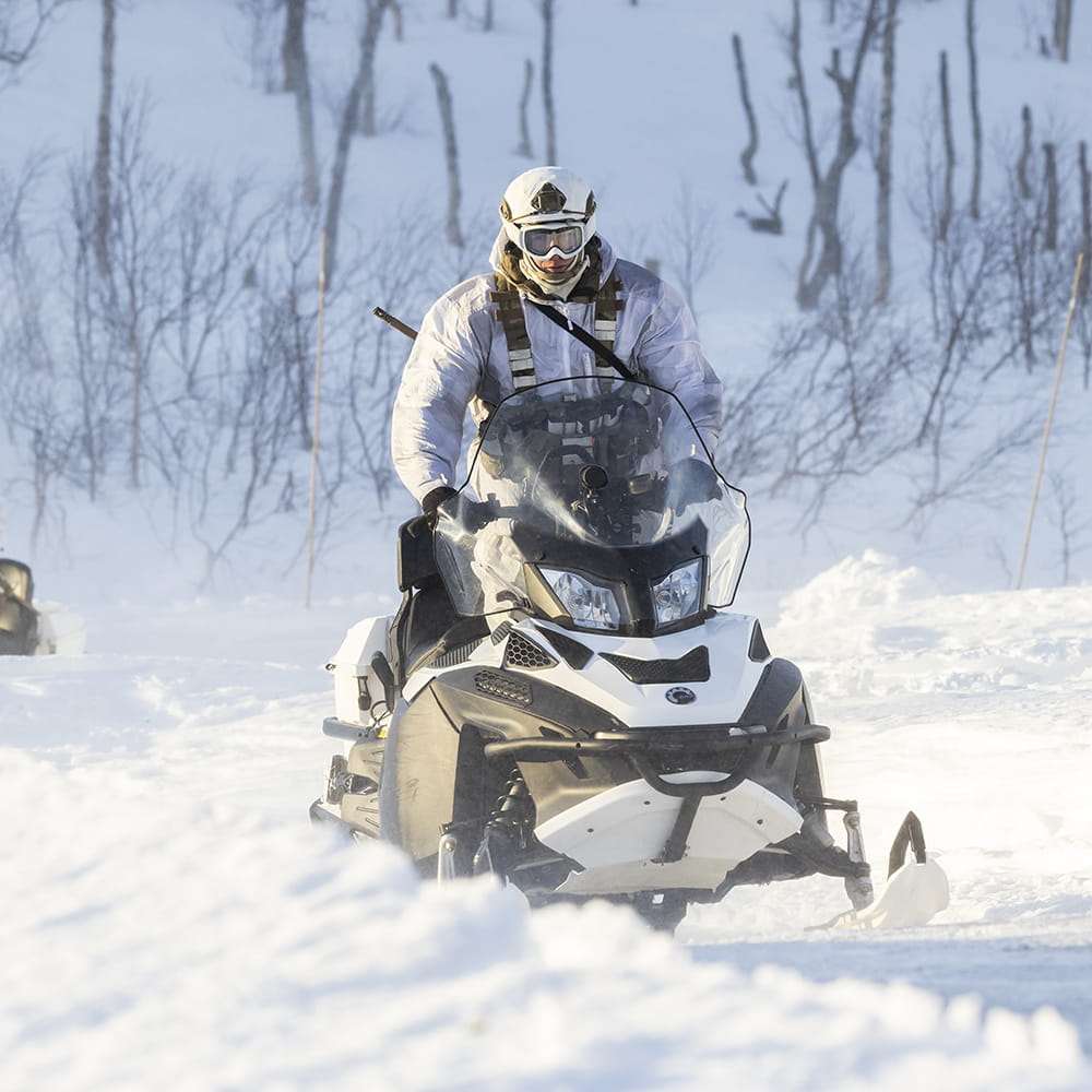 Royal-Navy-Royal-Marines-Equipment-03-By-Land Royal Marine in snow gear in arctic conditions using a snowspeeder