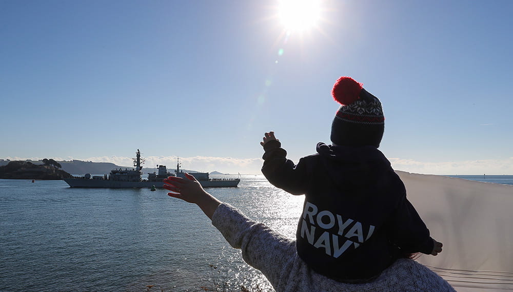 Royal-Navy-Families-11-Support-for-Children Small child with bobblehat on parent's shoulders waving off HMS Montrose