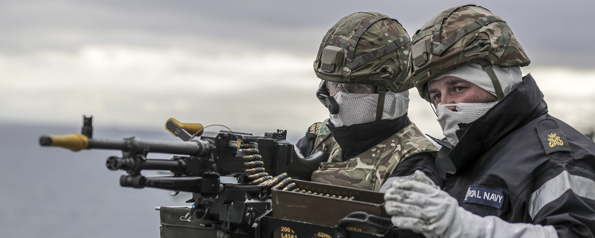 Two Royal Navy sailors firing a heavy machine gun