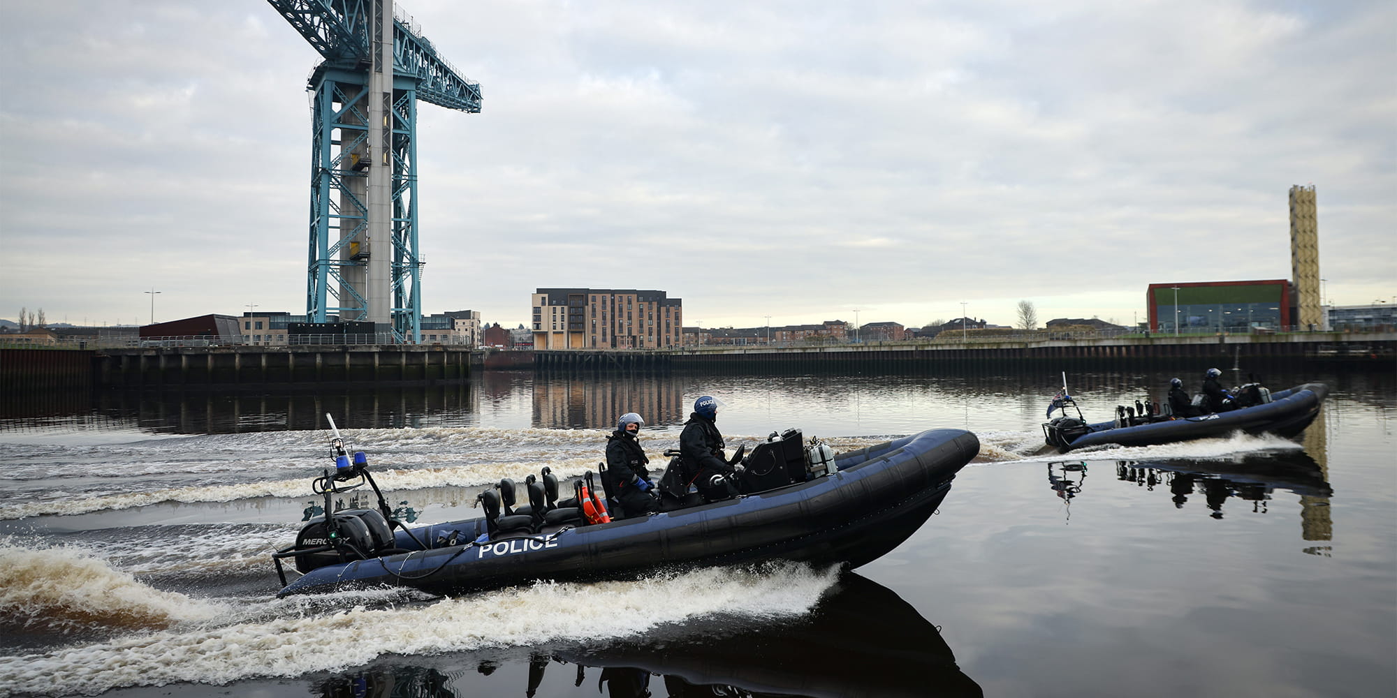 2 police rib boats race through the port at speed