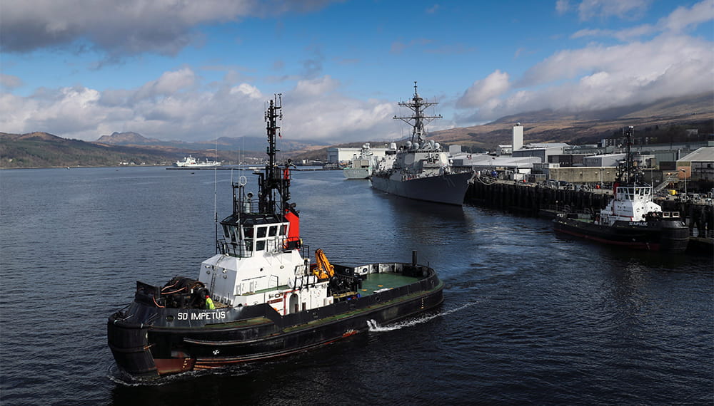 SD Impetus in foreground of image with a daring destroyer docked in port Cyde in the background