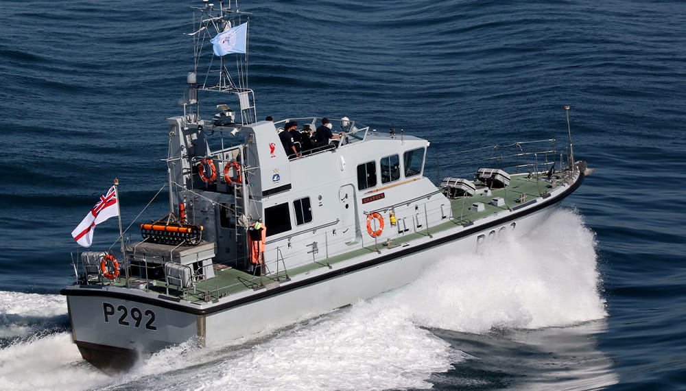 An archer class boat drives at speed away from the camera