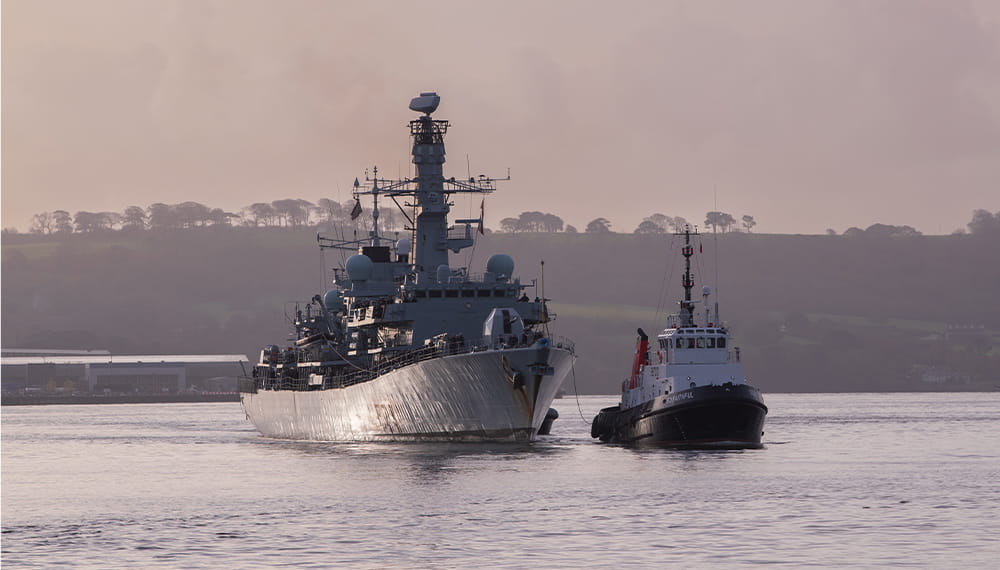 A Duke class frigate and a harbour patrol boat coast towards the camera at dawn