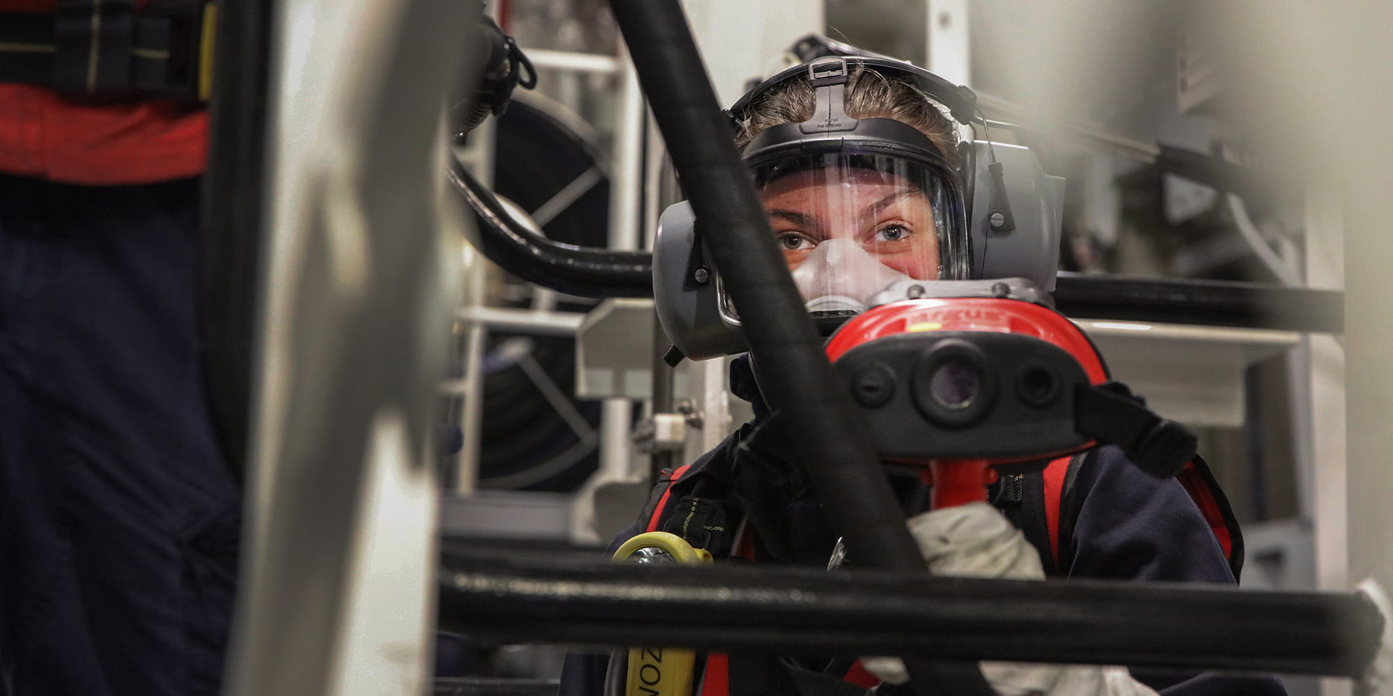 A navy sailor in a face mask and ear protectors