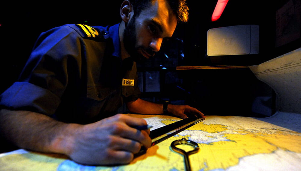 A Royal Navy sailor navigates a map aboard a Navy ship.