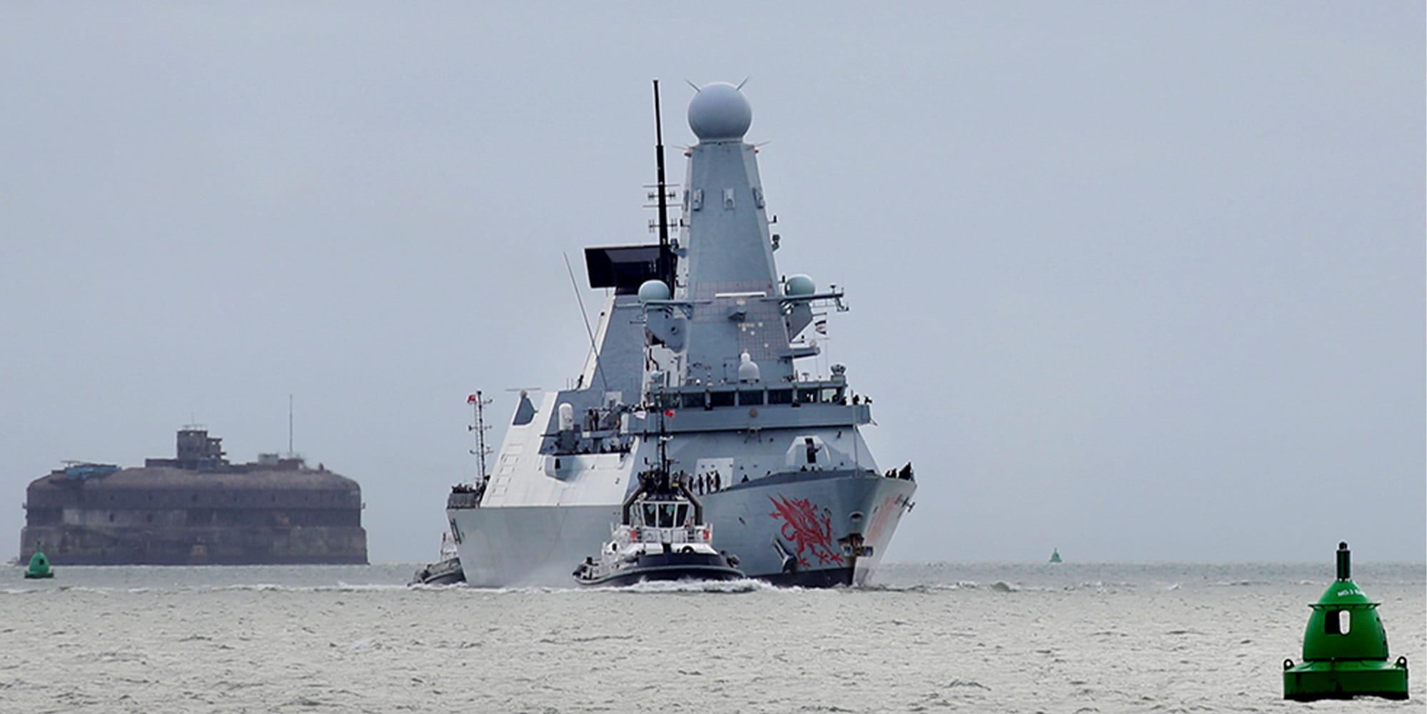 HMS Dragon sailing towards the camera with a smaller patrol boat alongside it