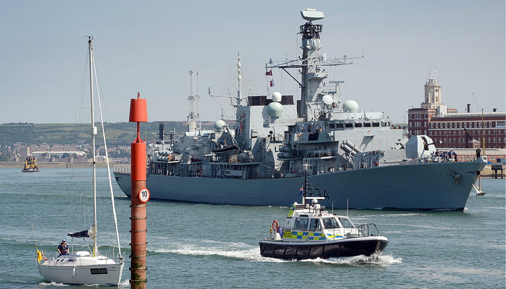 Warship arrives in Portsmouth harbour with a police patrol boat escorting it