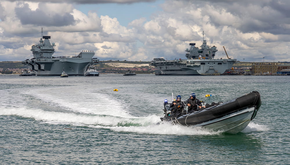 Police patrol rib boat headed towards the camera with the QE aircraft carrier and 3 other vessels in the background