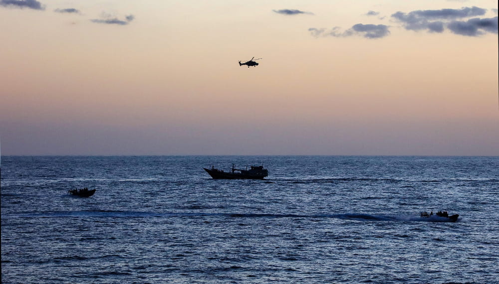 3 vessels in the sea at dawn with a helicopter flying overhead