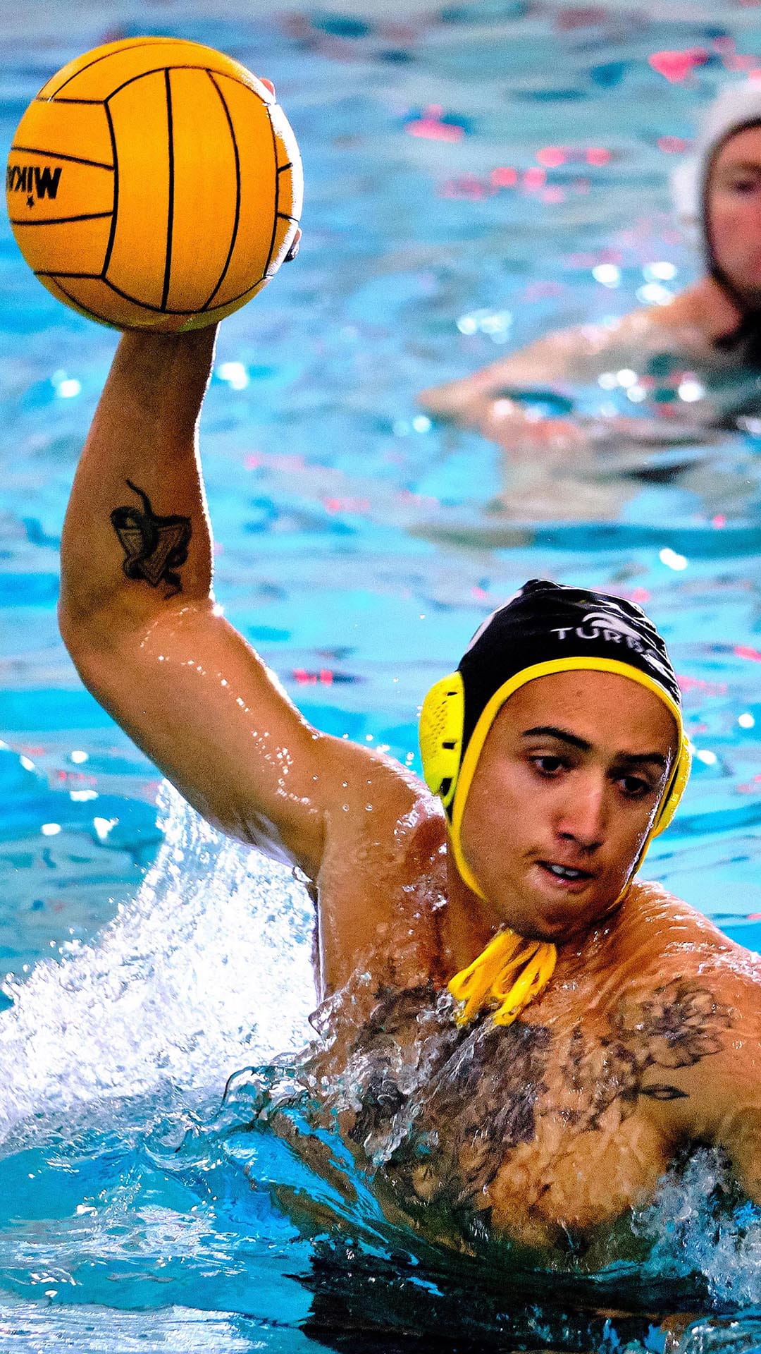 A man wearing a swimming cap and holding a ball in a swimming pool