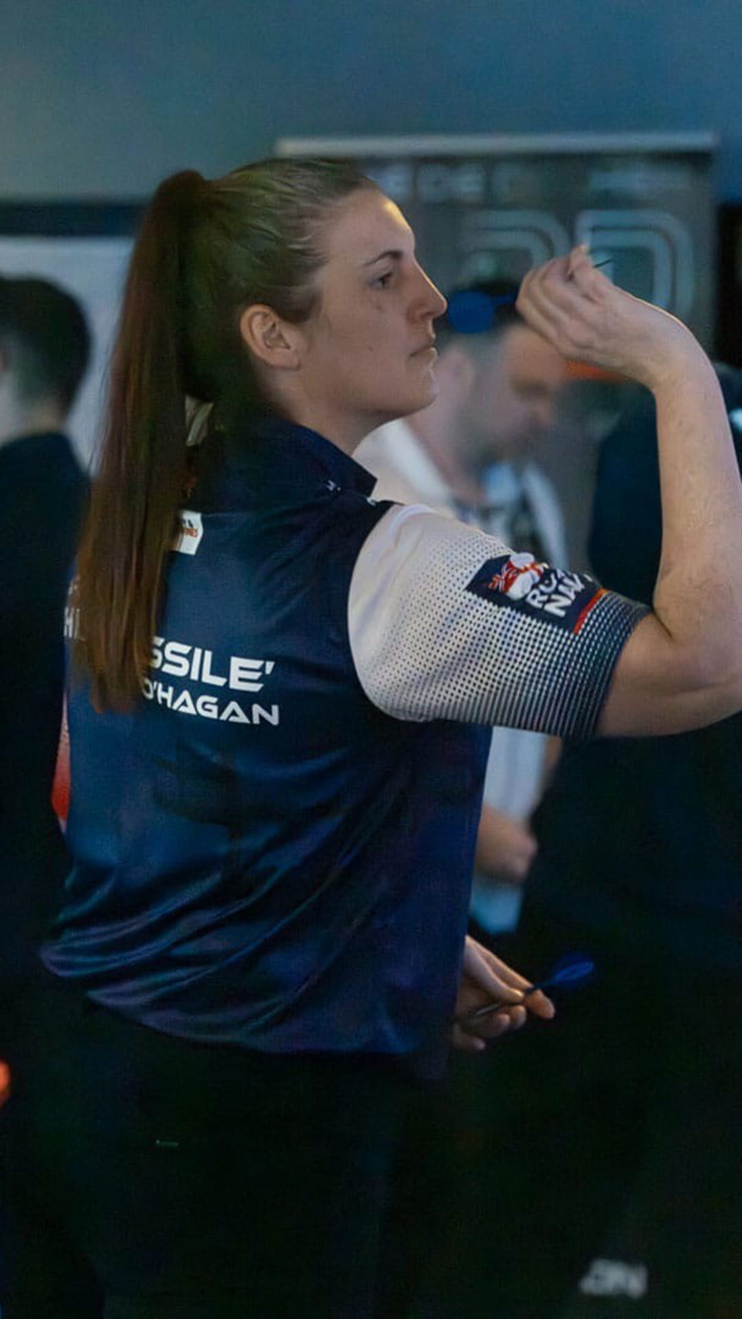 A woman preparing to throw a dartboard that is not seen