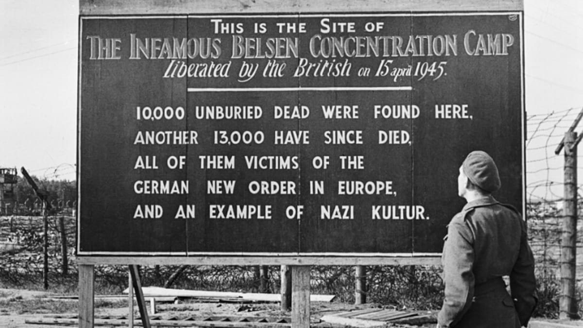 A soldier looks at the sign erected by the liberators of Bergen Belsen about the crimes within A soldier looks at the sign erected by the liberators of Bergen Belsen about the crimes within