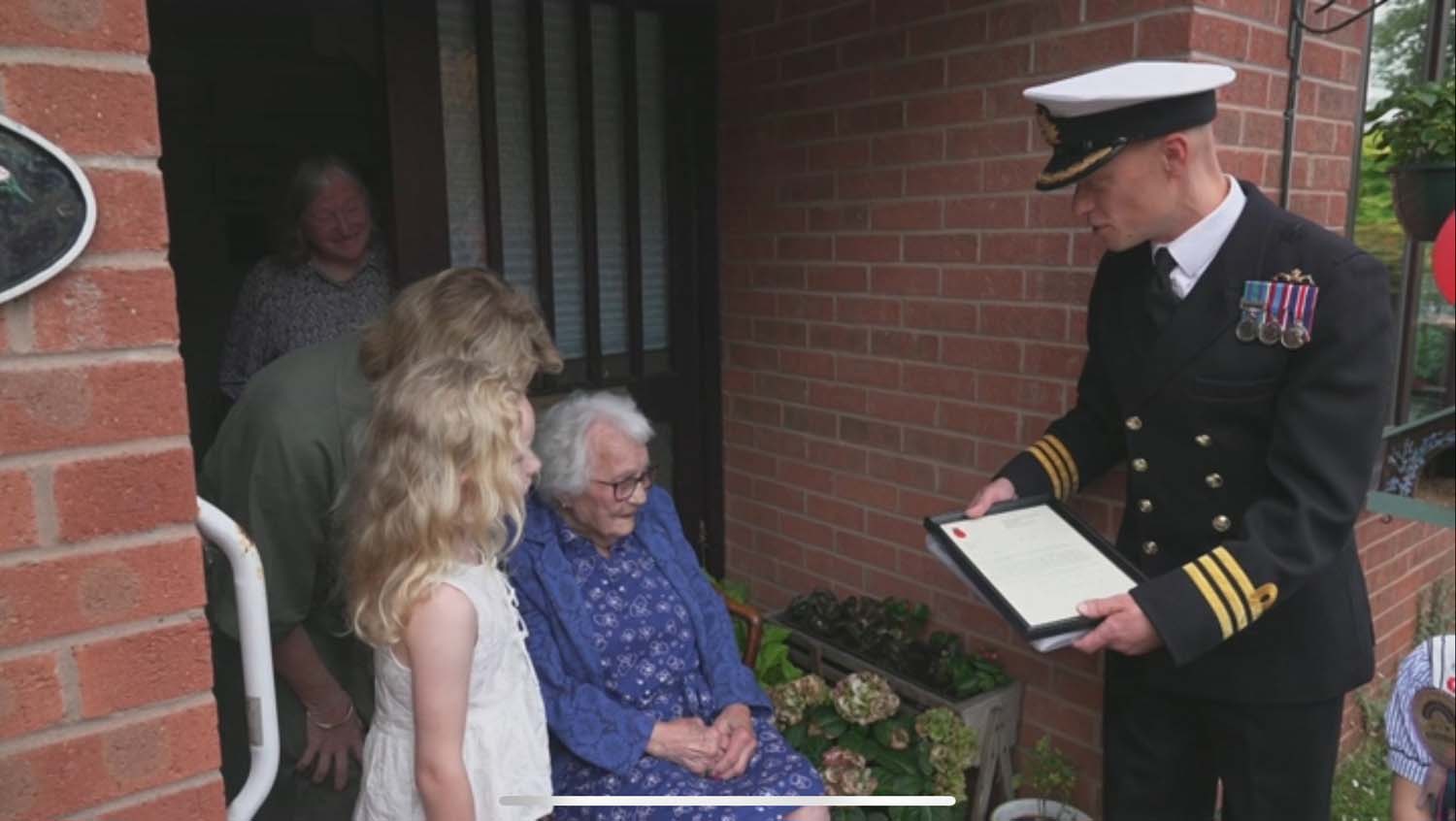 Commander Jonathan Richards presents Thelma Redman with her letter from the First Sea Lord General Sir Gwyn Jenkins RM