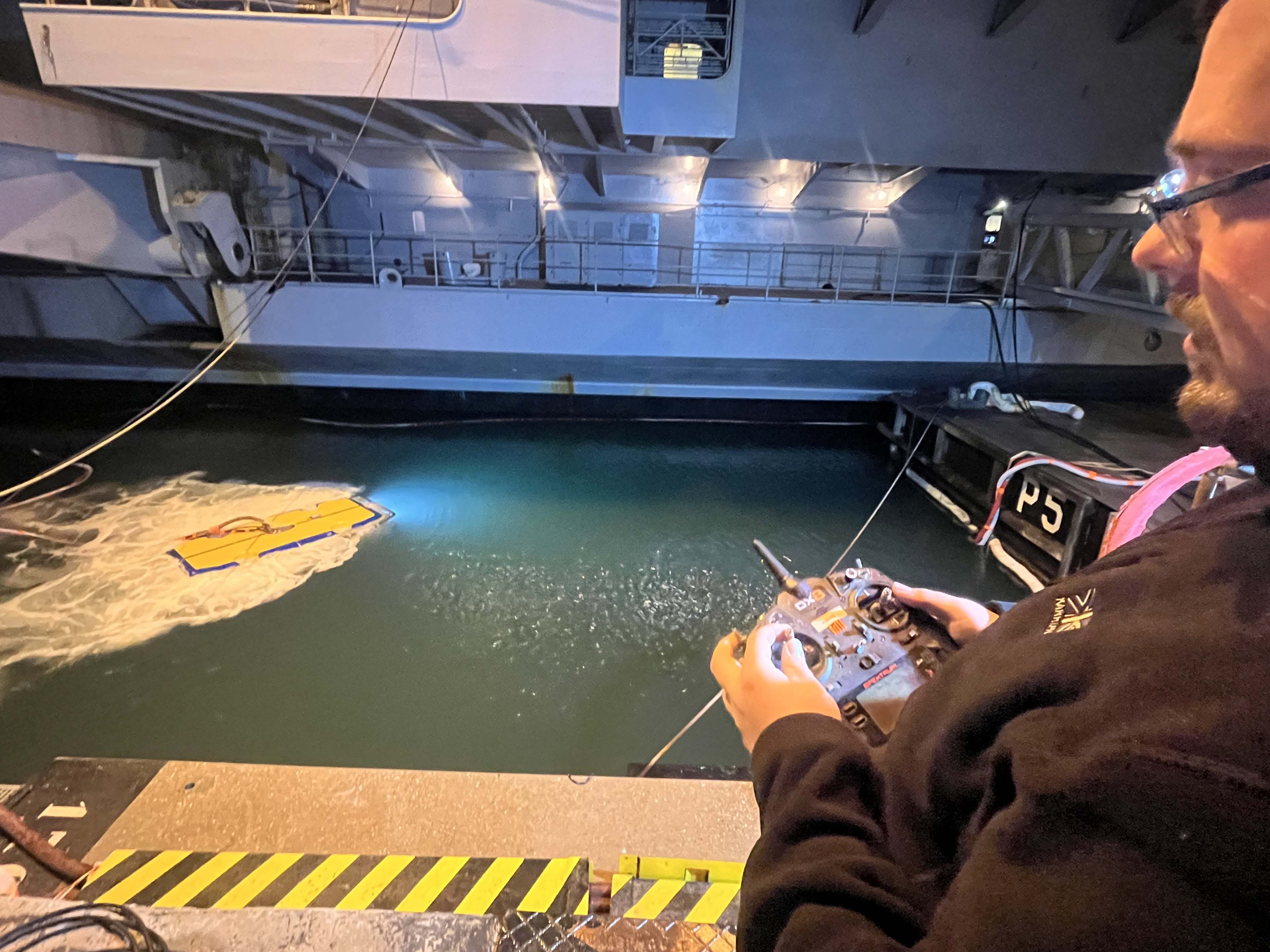 The hull cleaning drone operator manoeuvres it into position to inspect Charles de Gaulles hull