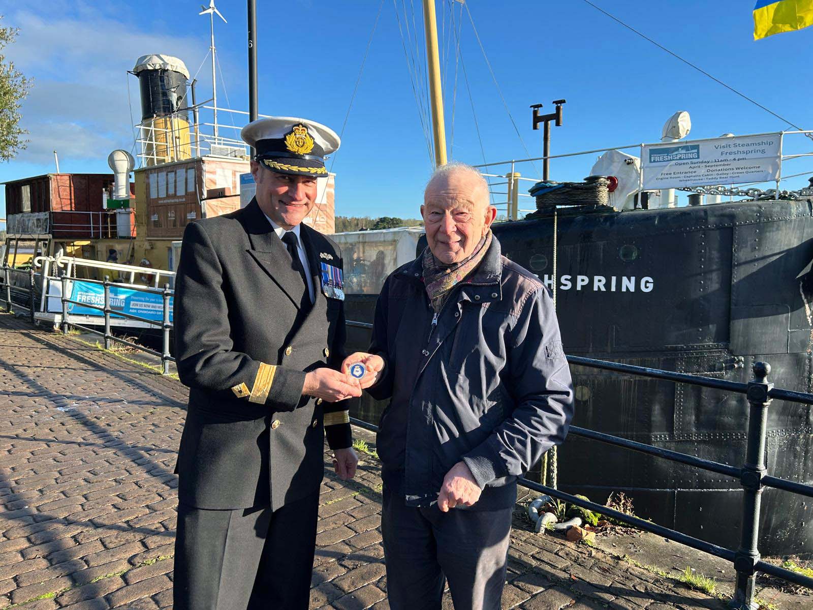Cdre Shattock presents a challenge coin as a thankyou for Freshsprings hospitality