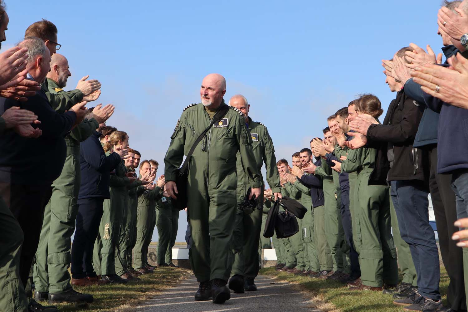 Personnel from RNAS Culdrose applaud Stephen Beirne followed by Ian McDonald as they make their back to 750 Naval Air Squadron after their last flight.