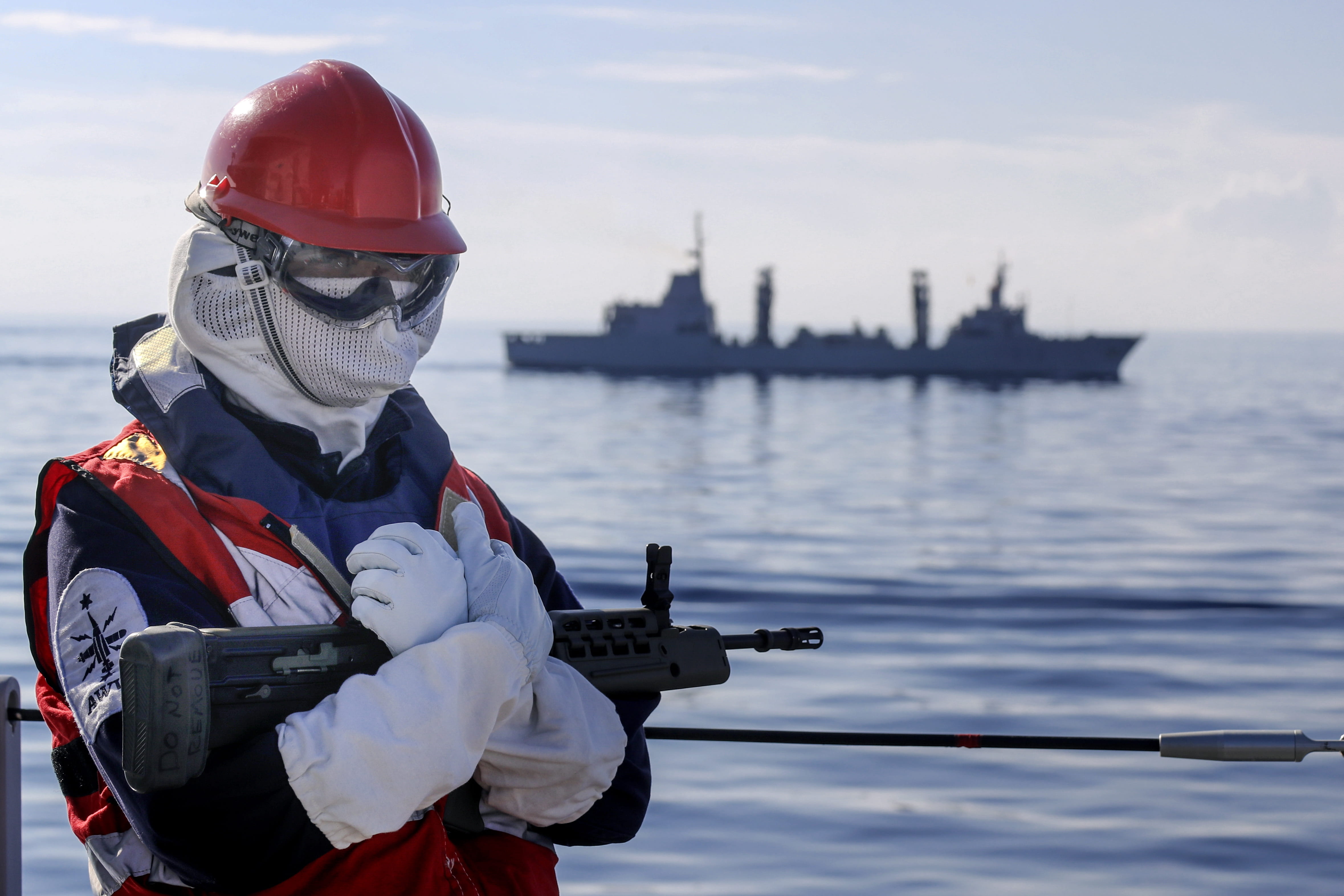 One of HMS Albion's sailors stands guard as the tanker ESPS Patino sails past