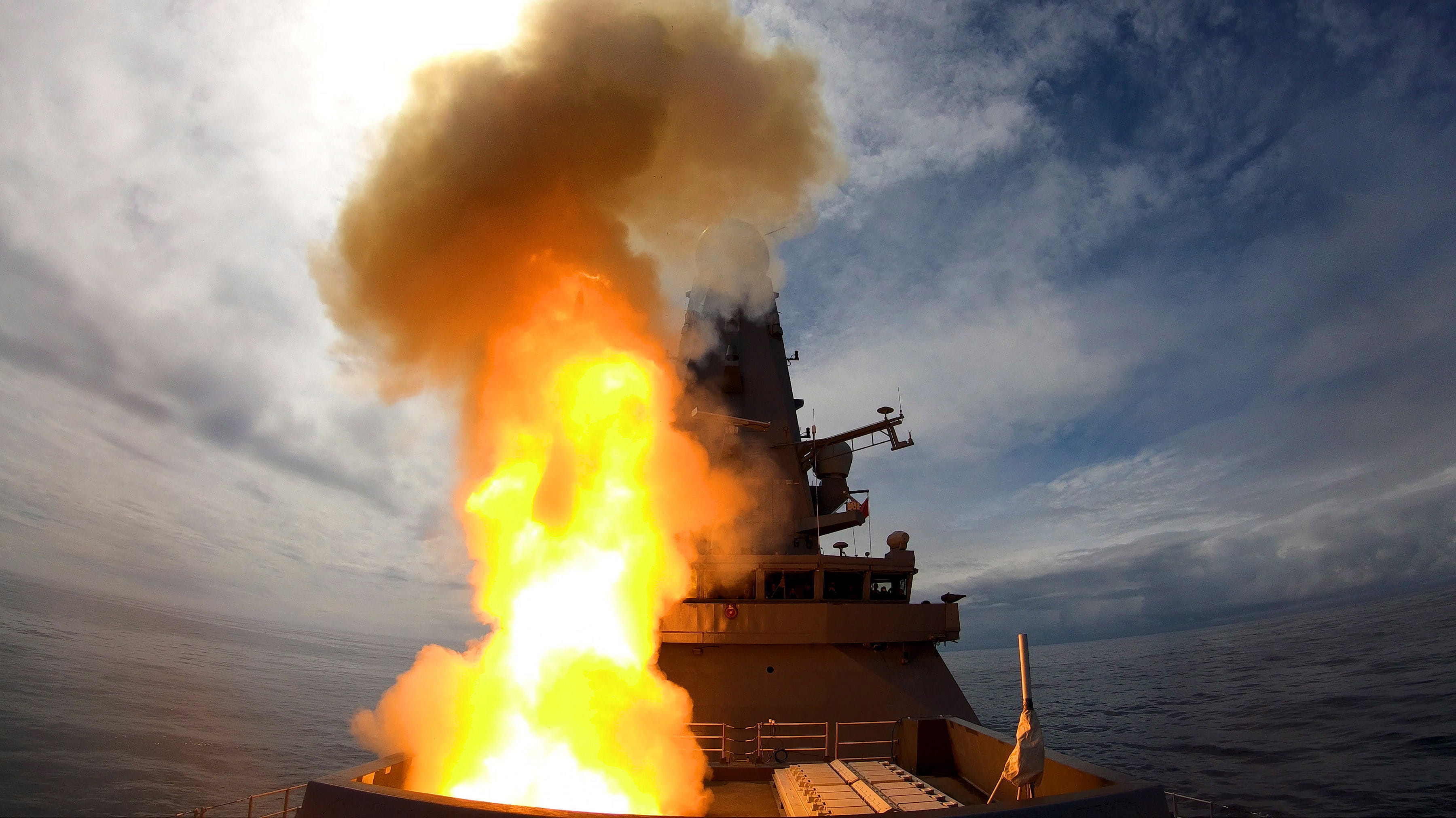 The forecastle of HMS Defender is partially hidden by fire and smoke as she fires a Sea Viper at Formidable Shield 2019
