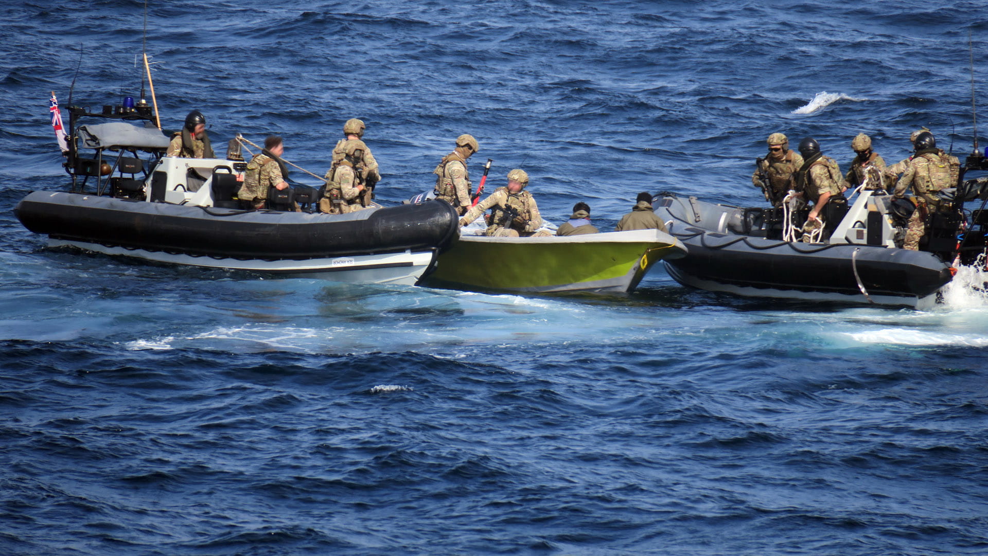 Two of Lancaster's sea boats flank the suspect skiff as Royal Marines retrieve the weapons cache