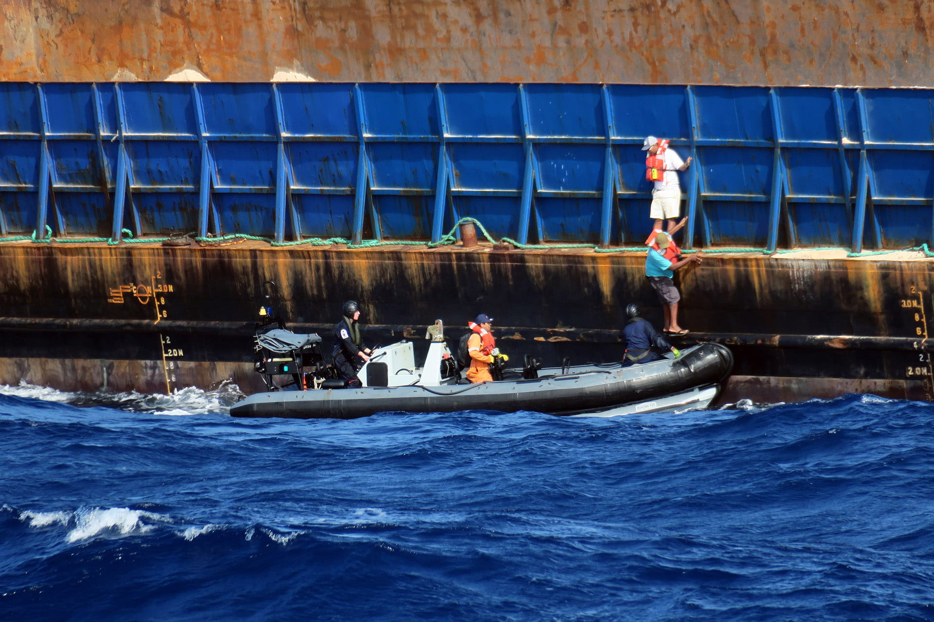 The tug crew step off the barge on to HMS Medway's sea boat The tug crew step off the barge on to HMS Medway's sea boat