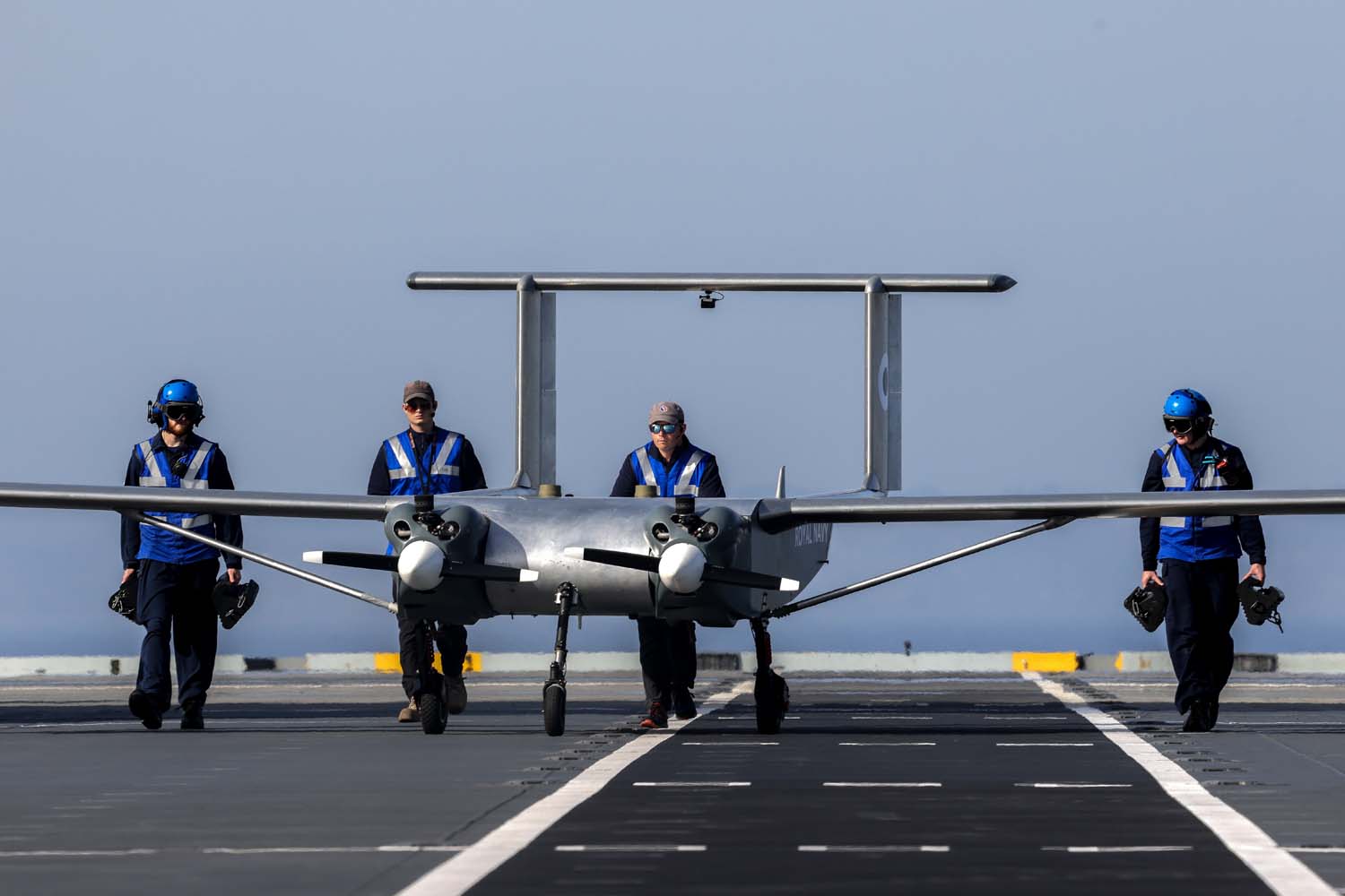 Naval airman aircraft handlers guiding the W Autonomous Systems (WAS) drone