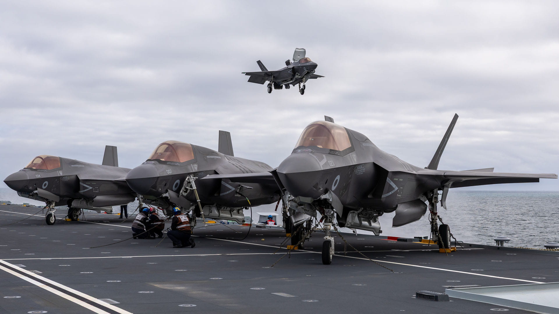 A storm of Lightnings - F-35s parked on deck with a fourth about to join them