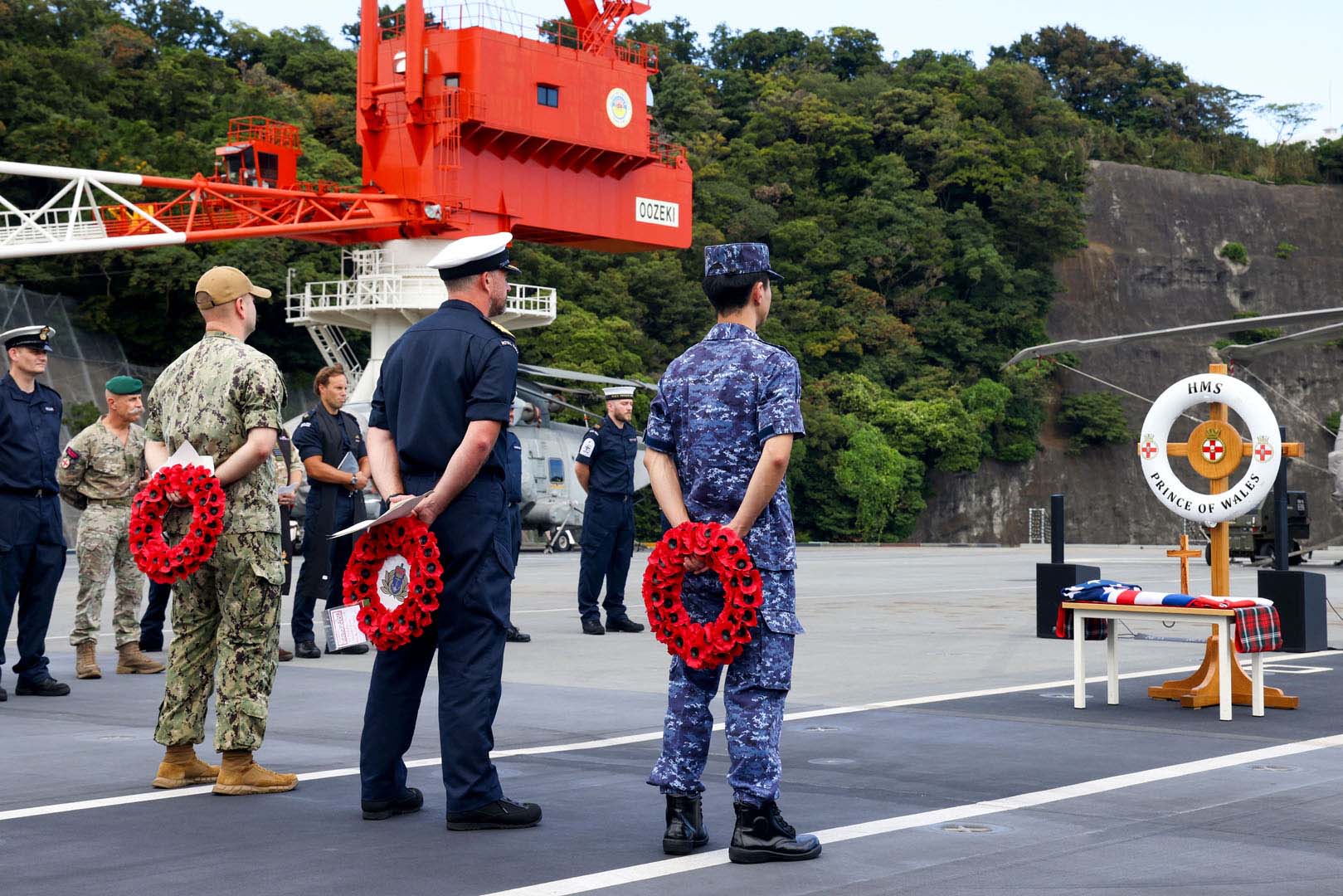 Lt Cdr Rogeness Capt Will Blackett and Lt Cdr Ihara prepare to lay wreaths on the makeshift memorial