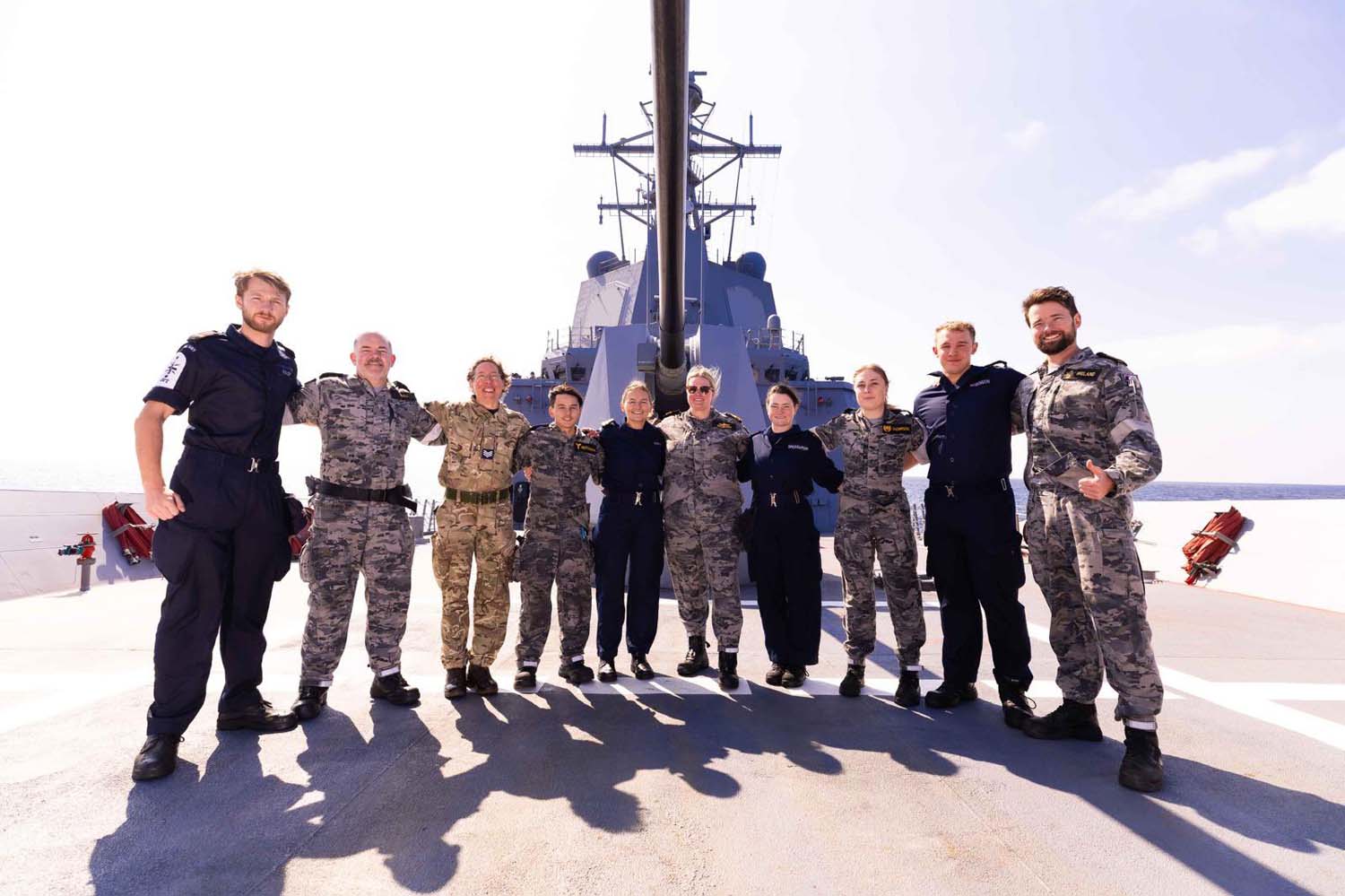 Spey's crew pose with Australian comrades under the barrel of HMAS Sydney's 5in gun