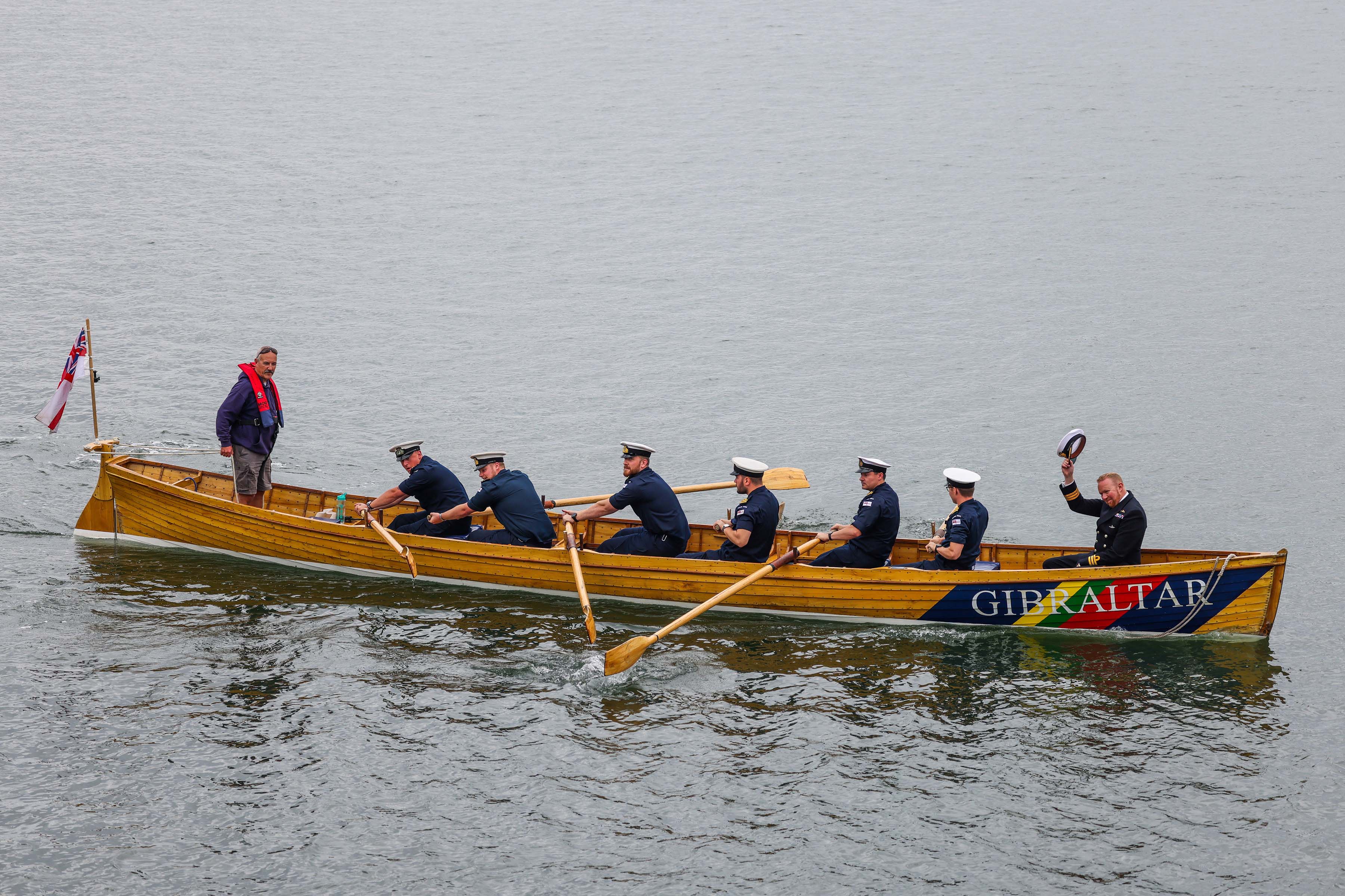 Commander Bate acknowledges the salute from his crew as shipmates row him ashore