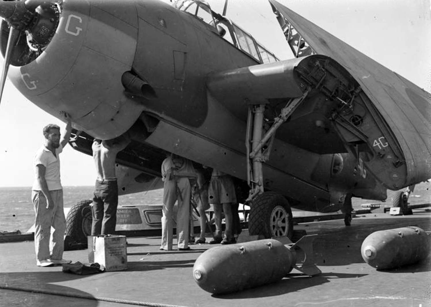 Armourers prepare an Avenger on HMS Illustrious for 'bombing up;