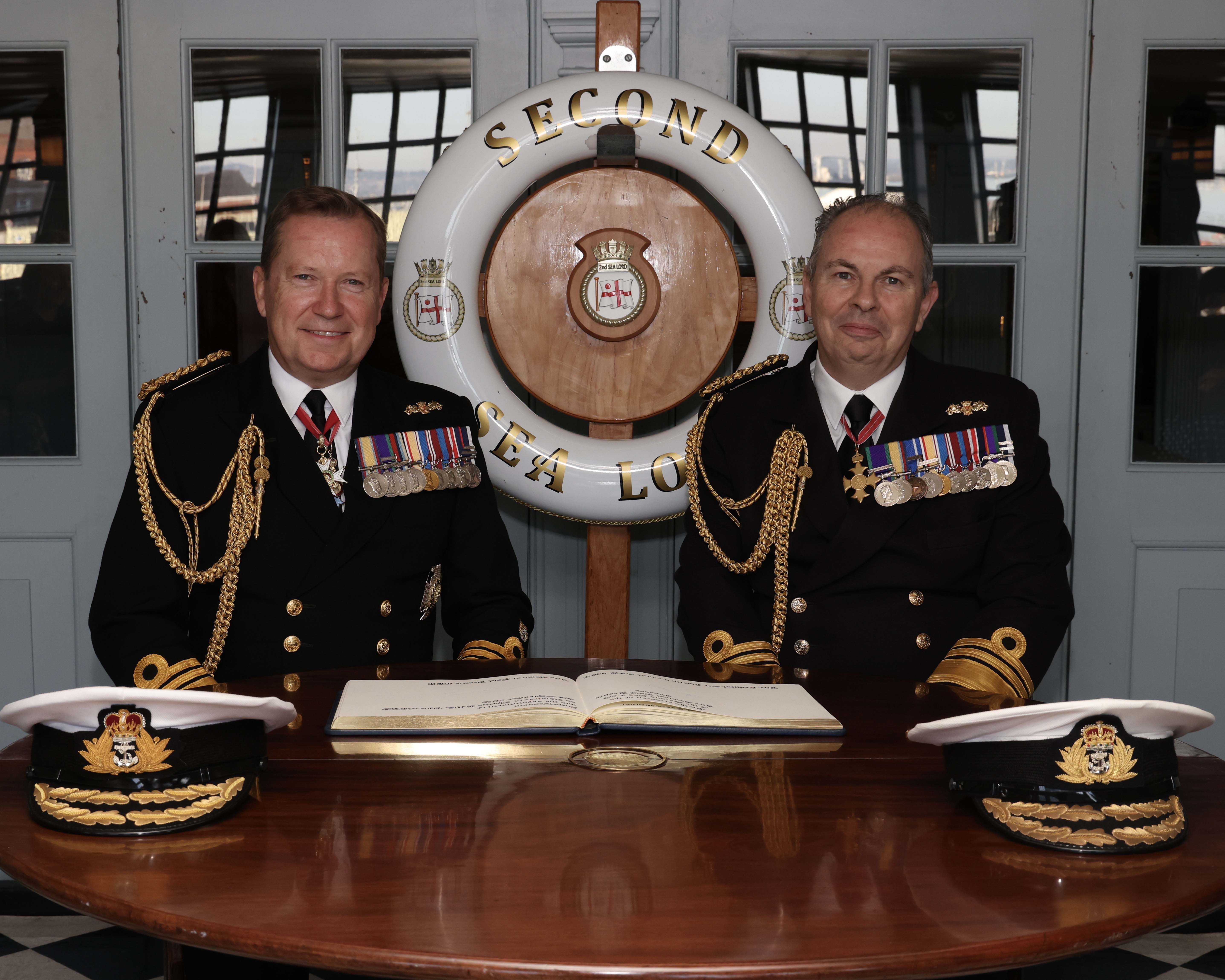 VAdm Sir Martin Connell KCB CBE signs over responsibility of 2SL to VAdm Paul Beattie CBE in the Admiral's Great Cabin on board HMS Victory as part of the supersession ceremony of Second Sea Lord.