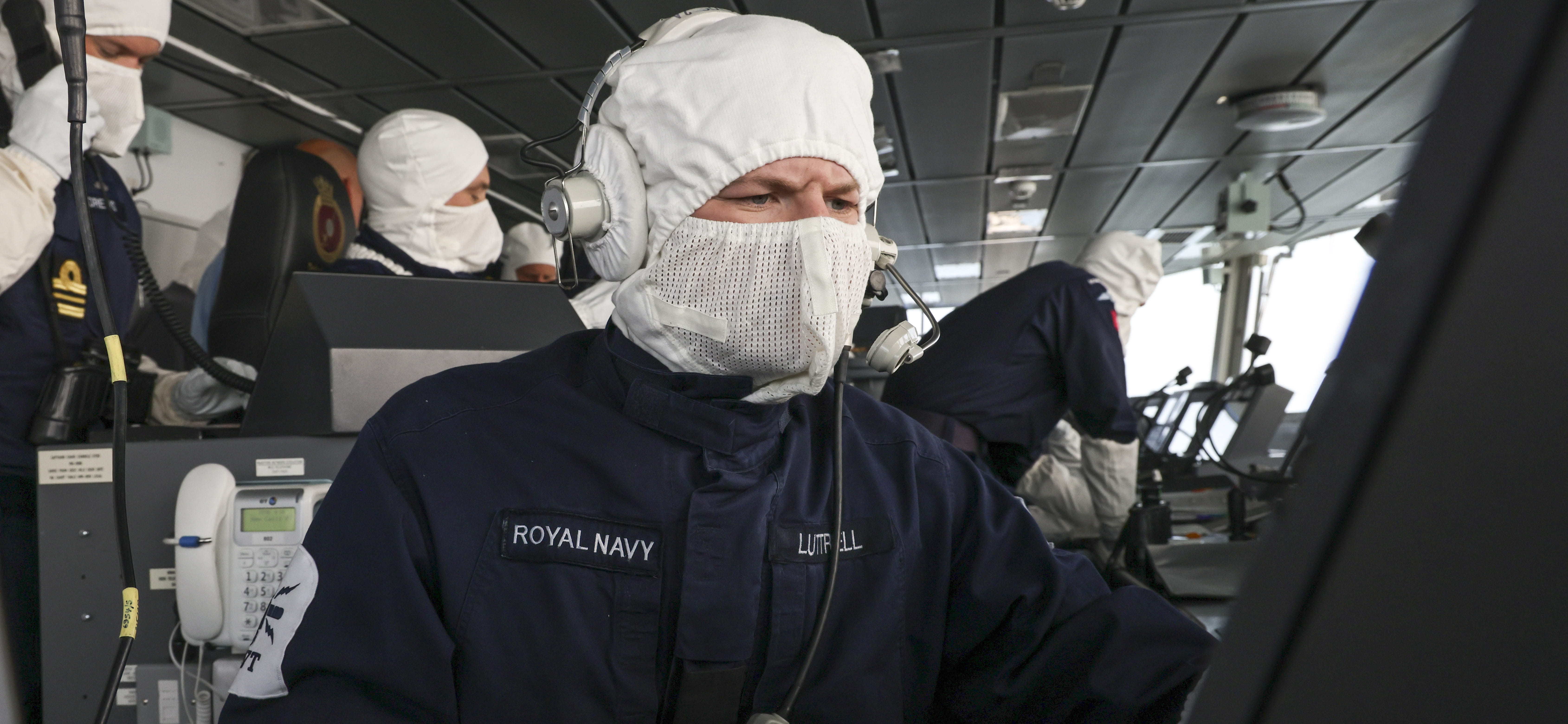 A sailor from HMS Defender's Bridge Team wears anti flash gloves and hood whilst checking navigation during Freedom Of Navigation Operations in the Black Sea.