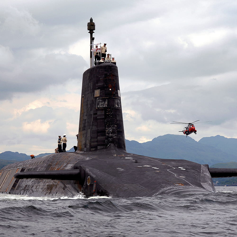 Royal-Navy-Organisation-submarine-service-03-unrivaled.jpg Royal Navy submarine on the surface with crew on the hull and helicopter flying overhead